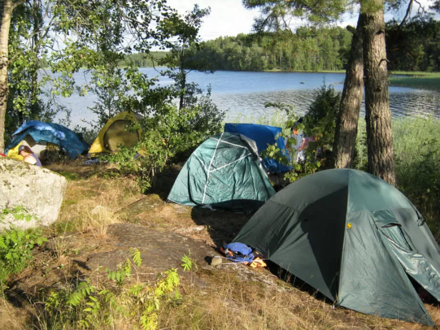 Лагерь на берегу озера. Красивые места для рыбалки. Палатка на острове. Место для отдыха на природе. Палатка у озера.